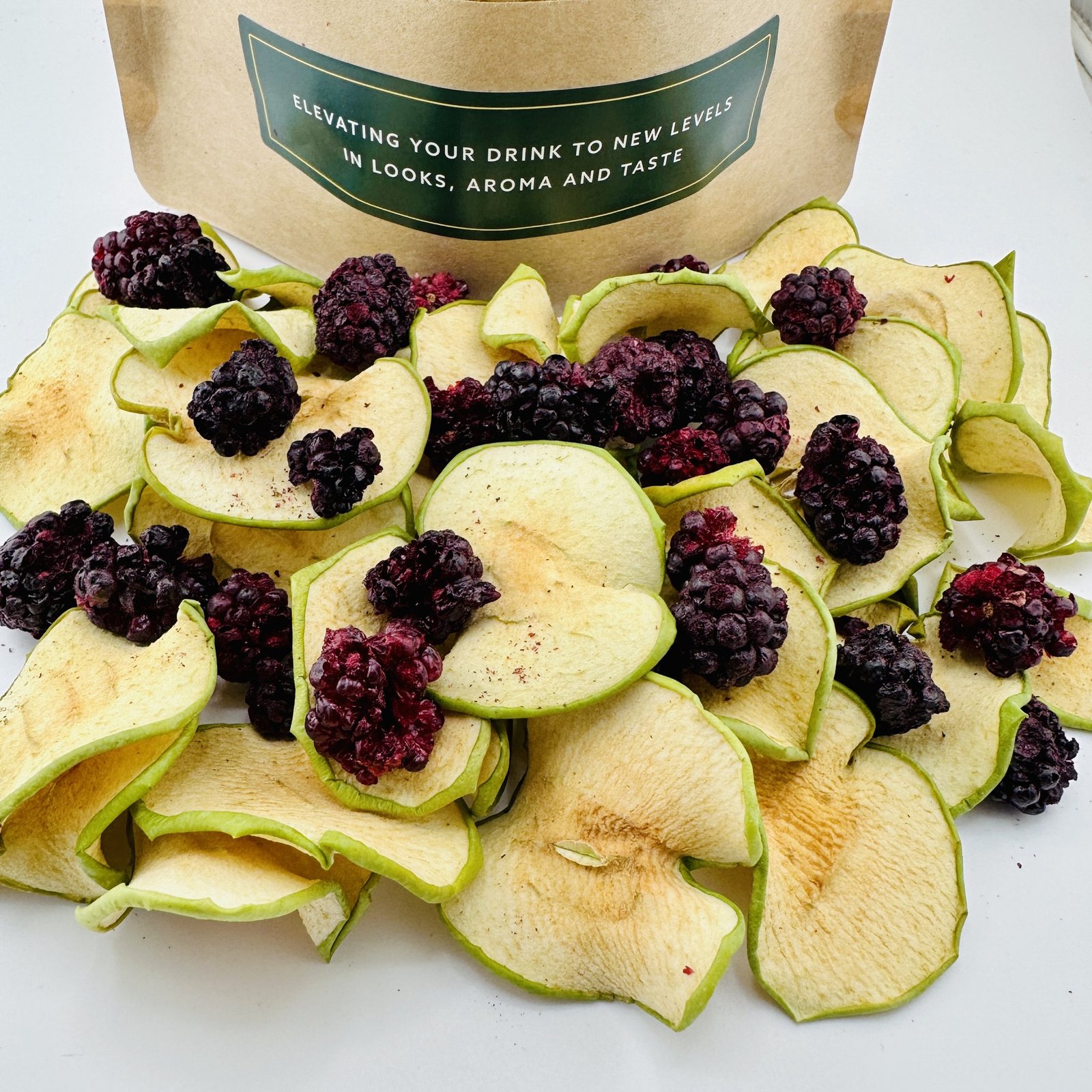 Dehydrated green apple and blackberry garnish pieces in front of a Fruitanicals pack