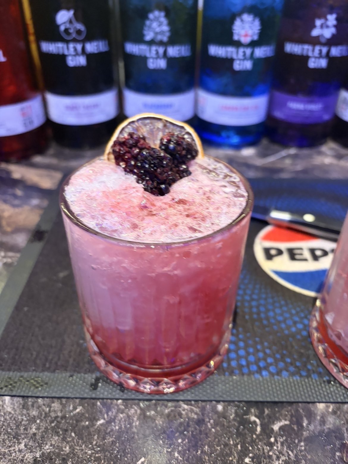 Bramble-style cocktail topped with dehydrated apple and blackberry garnish