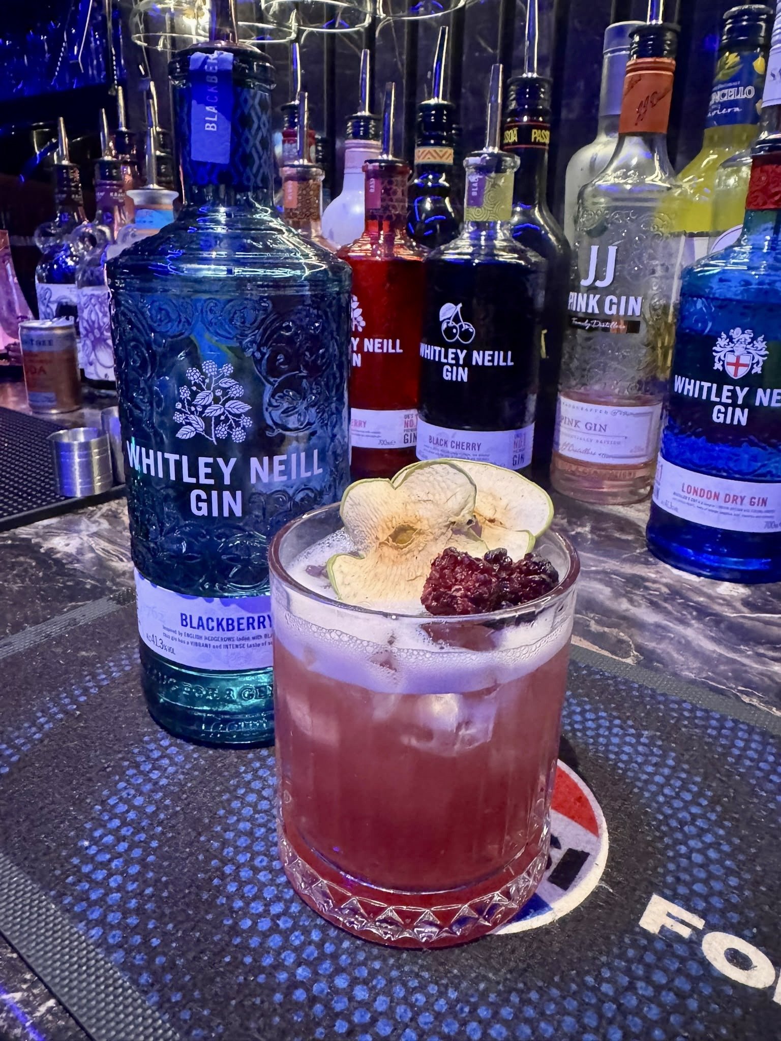 Blackberry gin cocktail garnished with dehydrated apple and blackberry